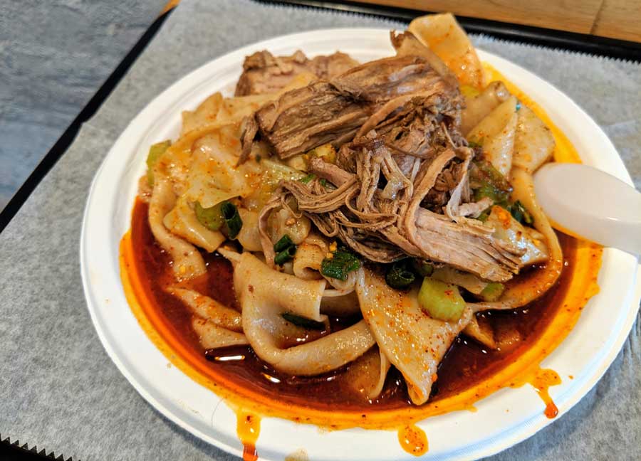 A bowl of spicy chicken noodles from Noodle Village