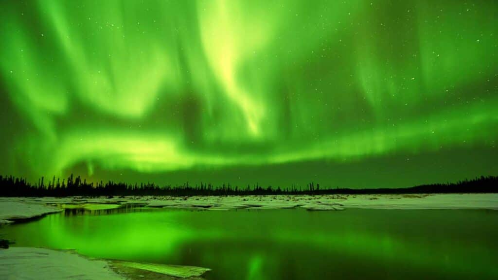 The reflection of the glowing northern lights on a lake