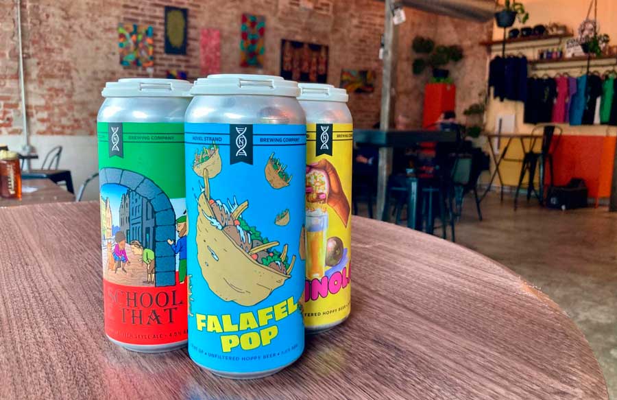 Canned beers on top of a table inside Novel Strand Brewing Company