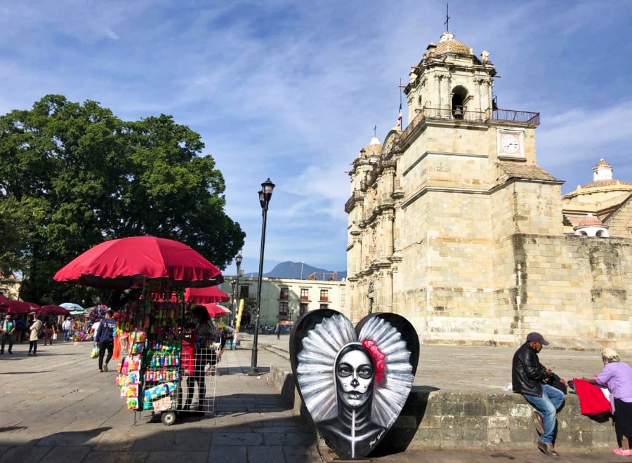 View of people enjoying the street of Oaxaca City Center with a small mural of a skeleton