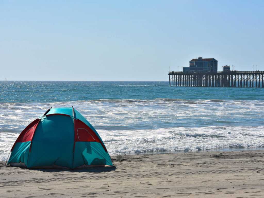 View of a tent near a beach and the Oceanside Beach Pier from afar