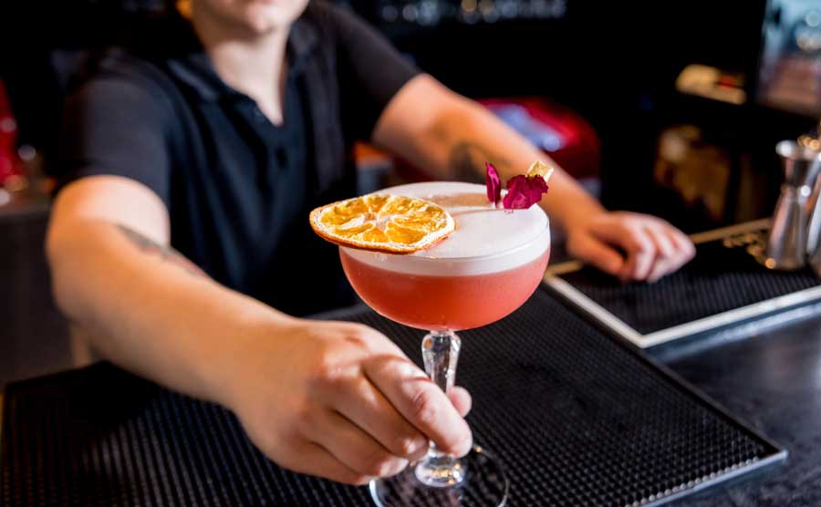 A bartender holding a glass of cocktail