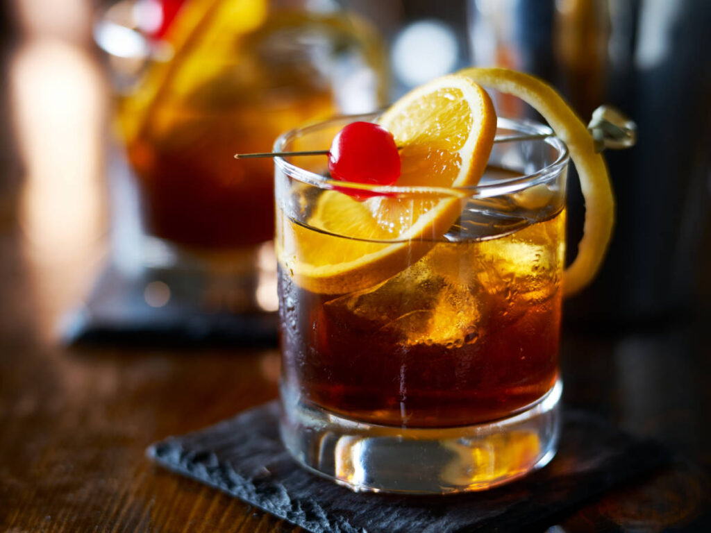 An Old-Fashioned cocktail with a sliced of orange on a glass