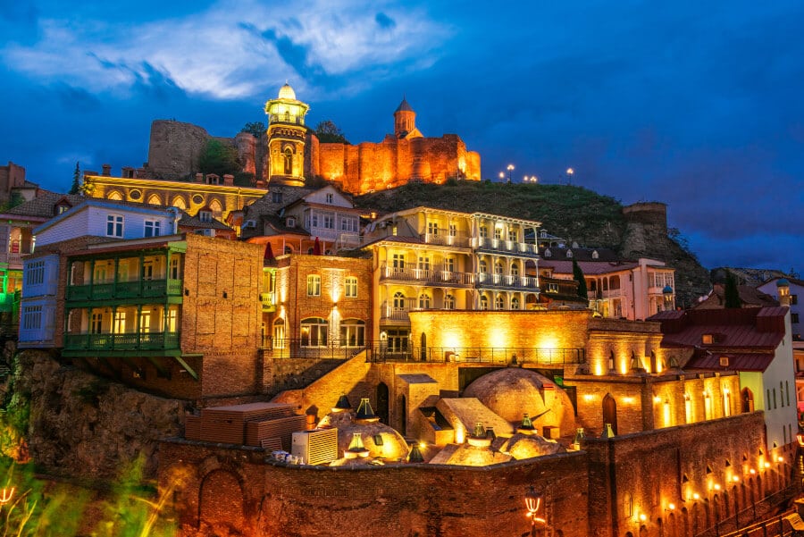 Illuminated view of the colorful buildings on the mountain cliffs at dusk