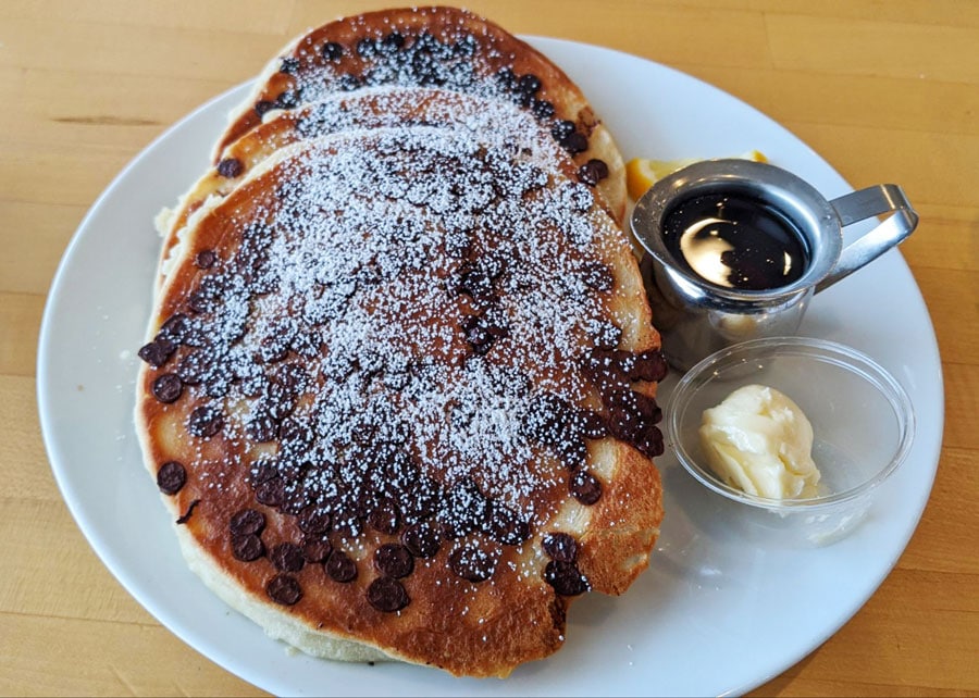 Chocolate chip pancakes on a plate with butter and syrup
