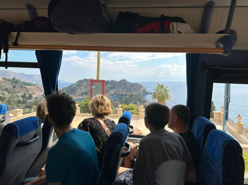 A group of people sitting on an Etna Transport shuttle bus to Taormina