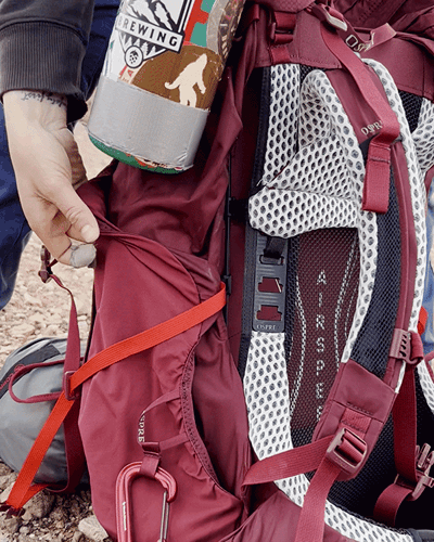 Skycie putting her watter bottle on the side pocket of the Osprey Aura AG LT backpack