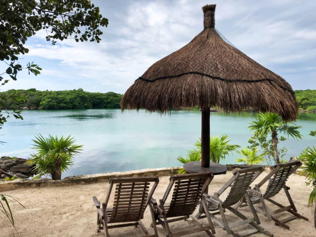 An outdoor seating area with a nipa umbrella near the Mexico Lazy River in Xel-Há Wildlife