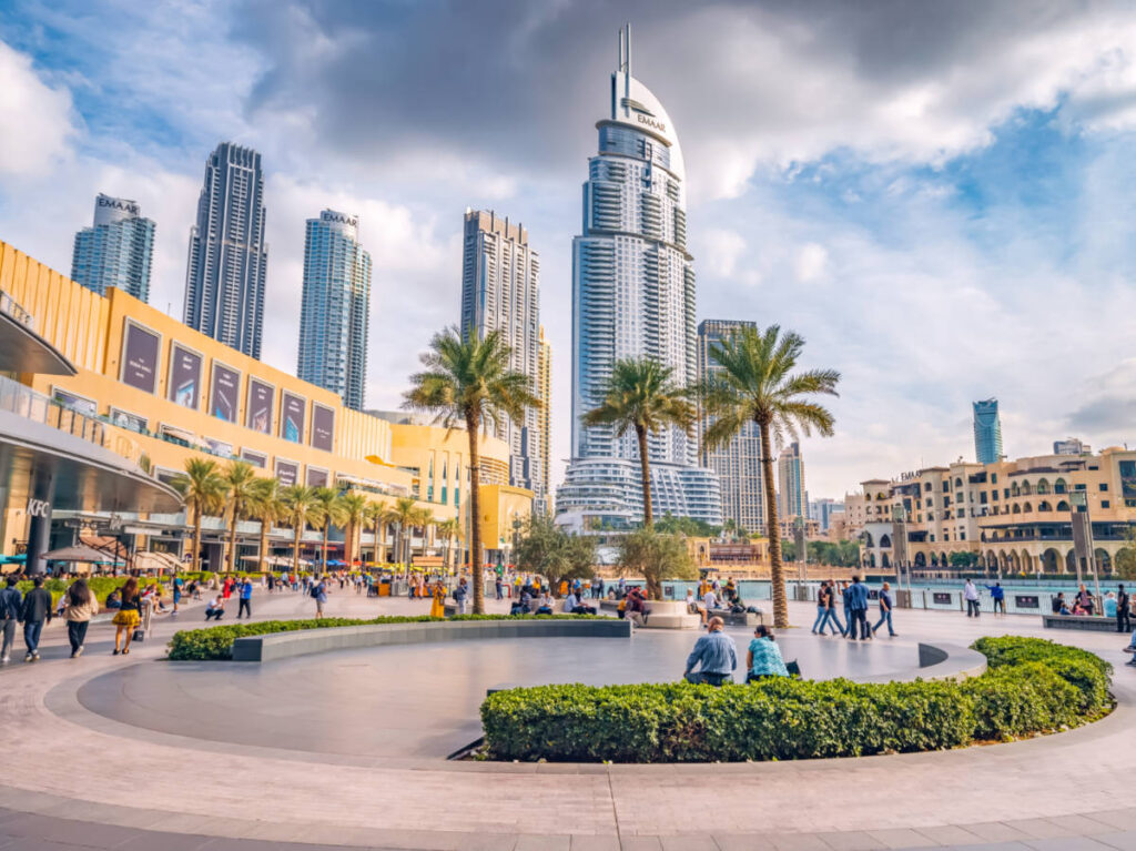 Crowd of tourists walking at the square near the entrance to Dubai Mall and on promenade embankment