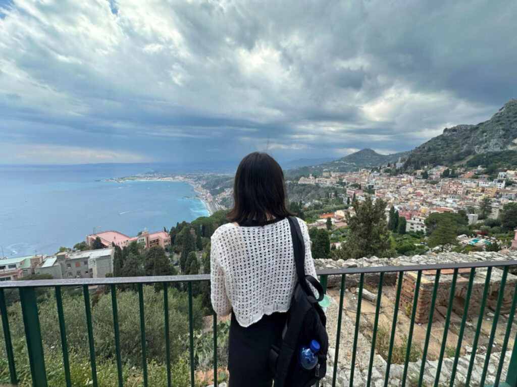 Author Lea Rose gazing at the cityscape of Taormina from the Teatro Antico di Taormina