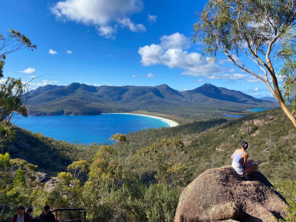 A woman on a rock looking at Wineglass Bay in Freycinet National Park