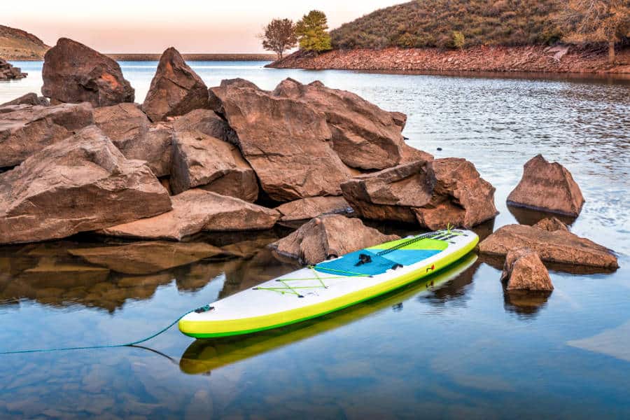 A paddleboard docked beside the rocky shore in Horsetooth Reservoir