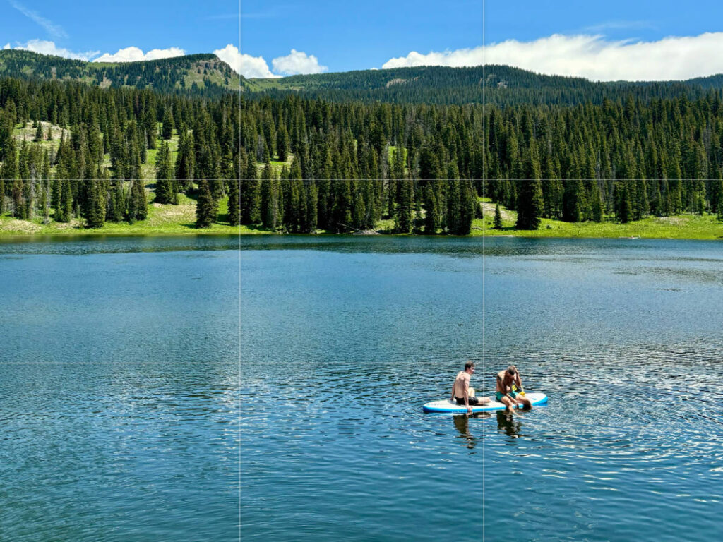 Two people paddle boarding on a serene lake