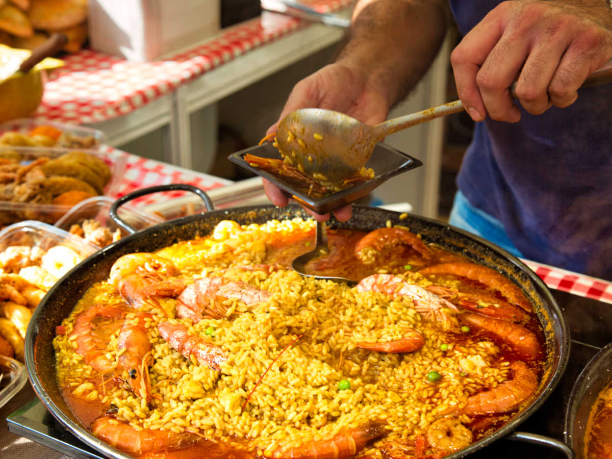 Closeup look of the vendor's hands preparing the paella