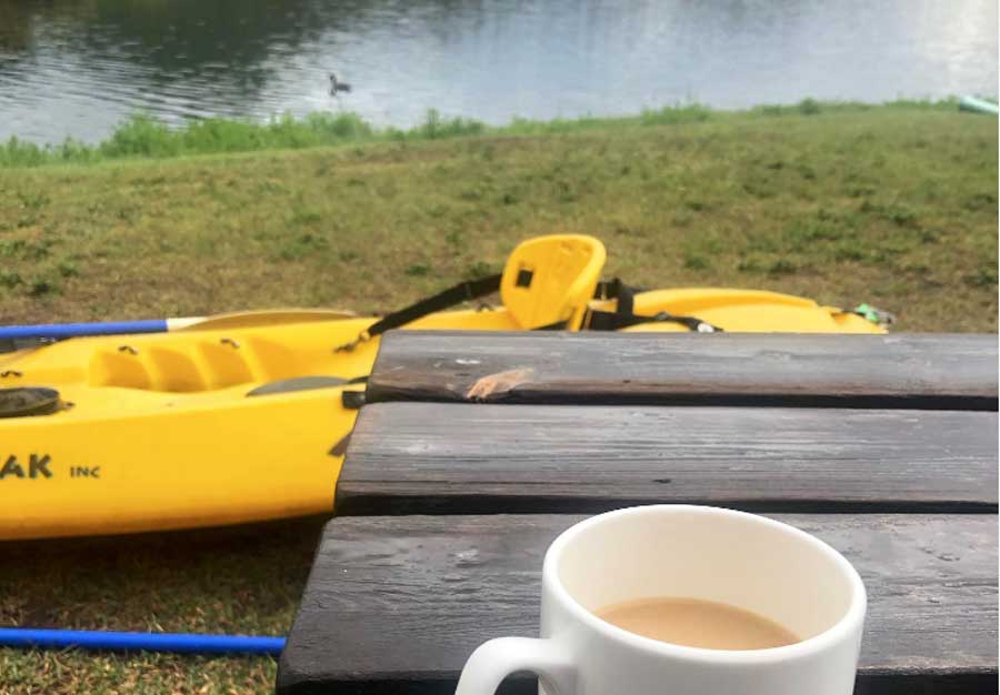 A cup of coffee on a table and a kayak boat near the Pagosa Lakes