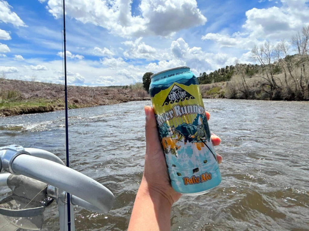 A hand holding a pale ale of Eddyline Brewery on the boat