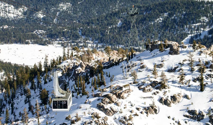 Panoramic view of a mountain ski resort with a cable car above.