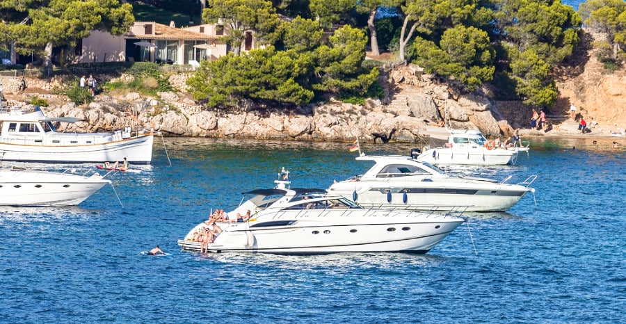 People swimming around the yachts on a local beach of Palma