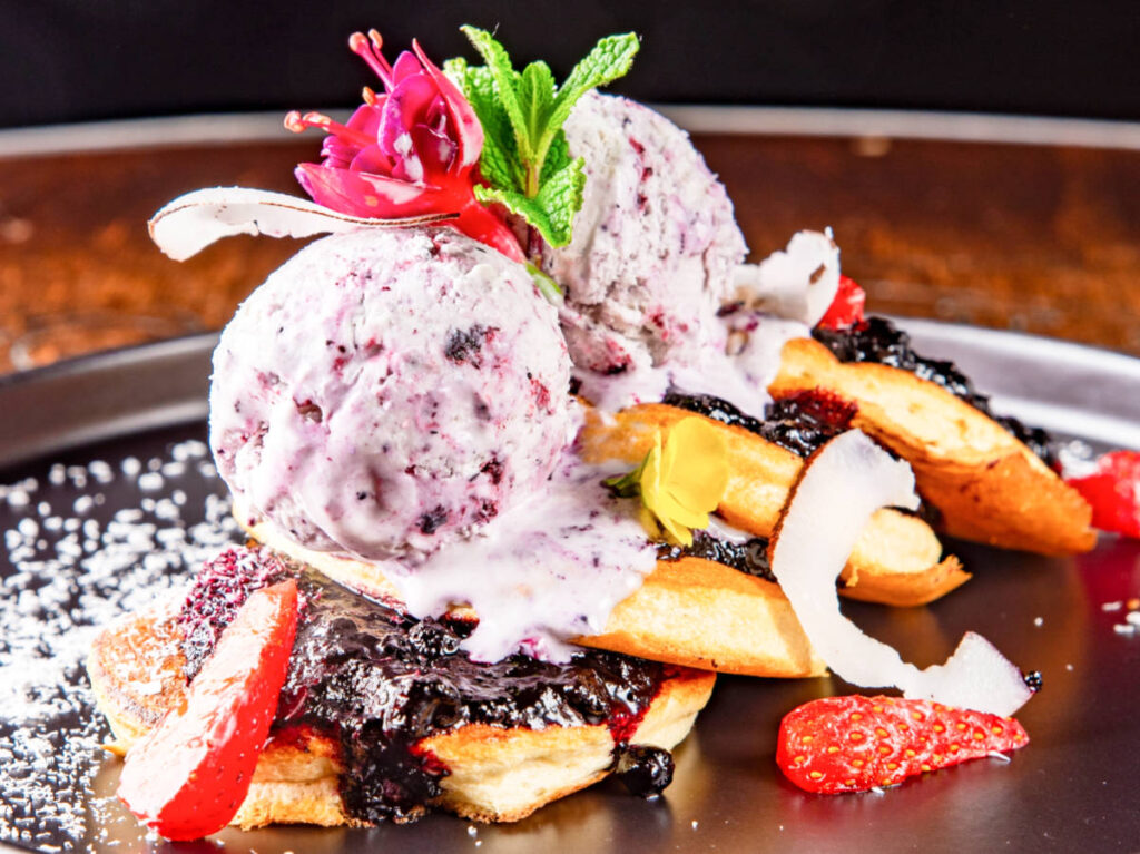 A plate of pancake topped with ice cream and strawberries