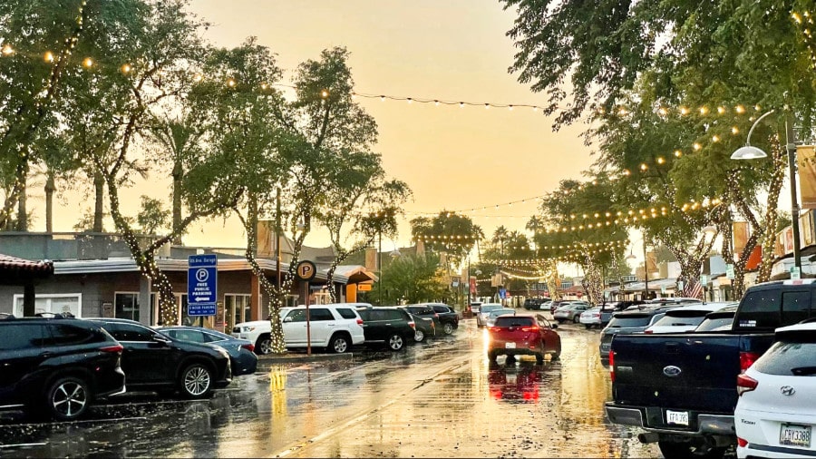 Rainy day in Old Town Scottsdale with parked cars around and string lights hung above the street