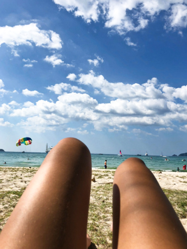 View of the legs relaxing along the shoreline of Patong Beach