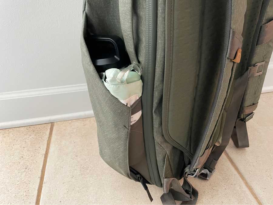 The side pocket of the Peak Design Travel Backpack that contains a water bottle and an umbrella
