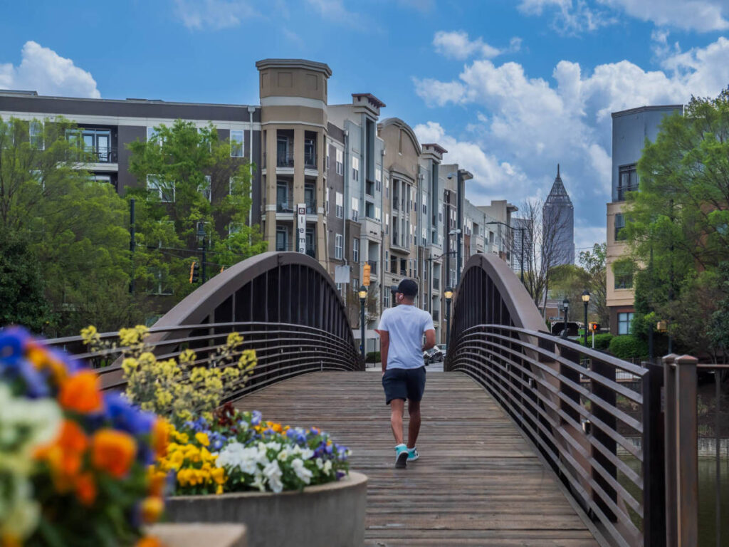 A man crossing on the pedestrian bridge over the lake at Foundry Park
