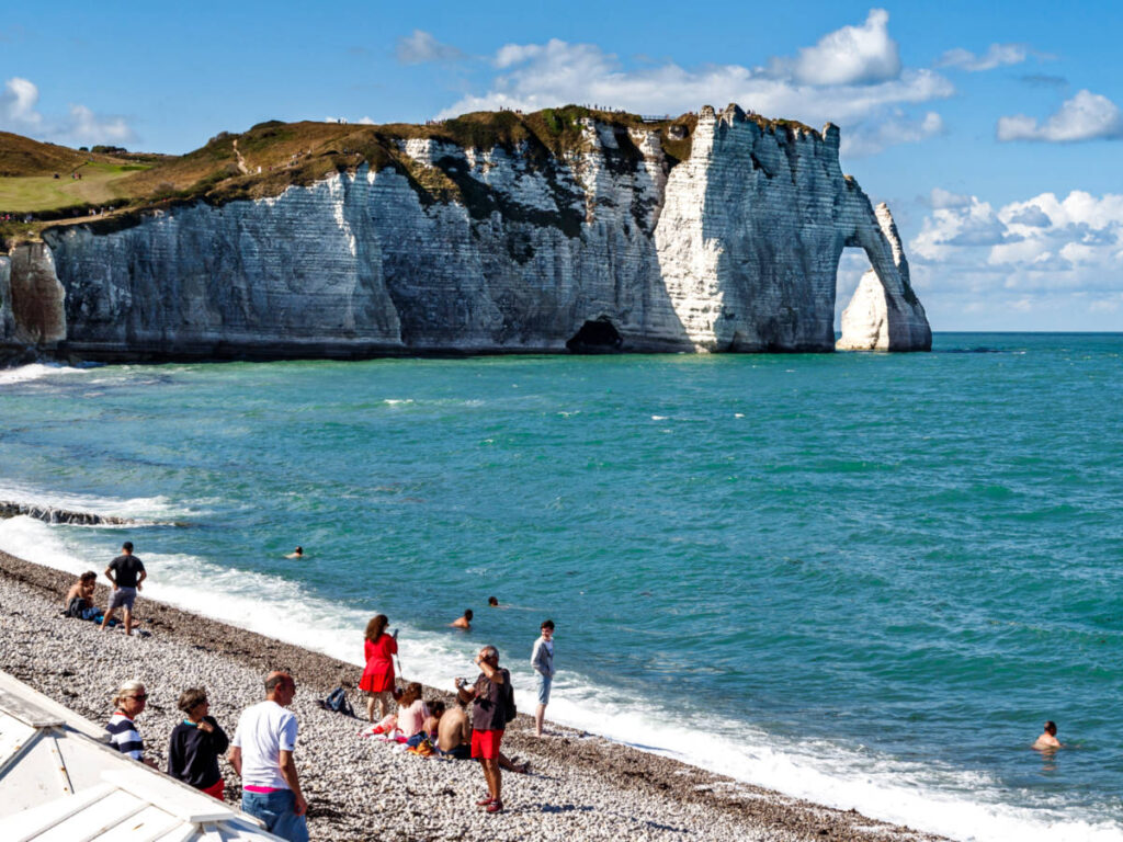 The people enjoying the beach with a scenic view of the Cliff at Étretat