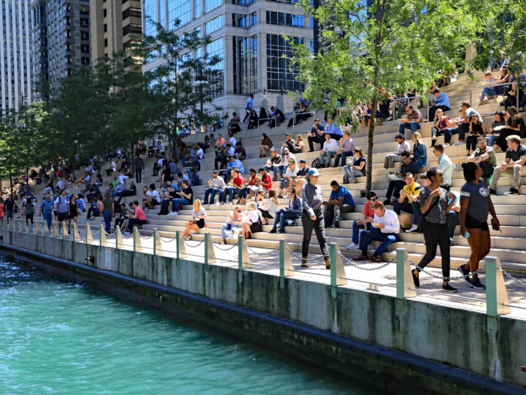People sitting on a staircase along the Chicago River