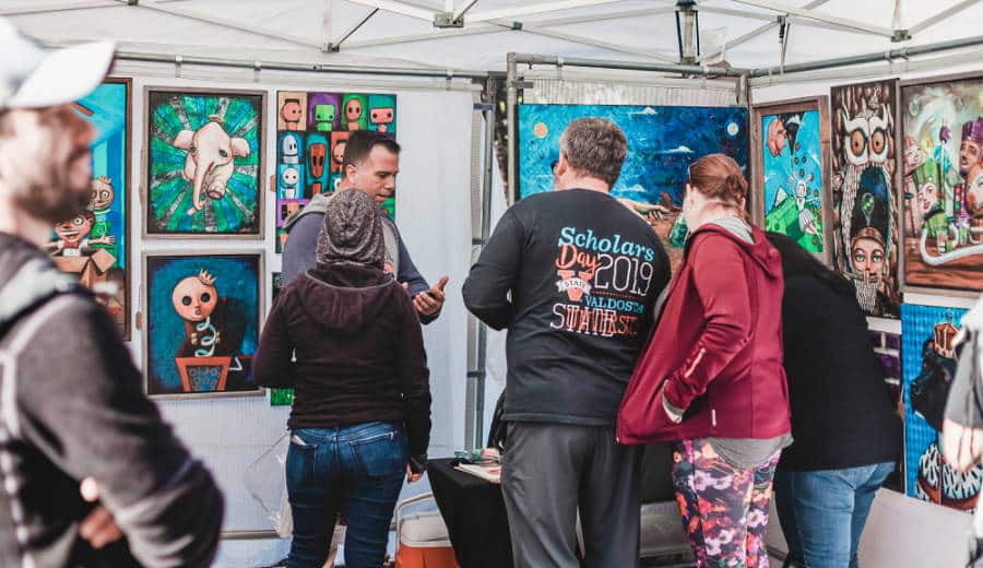 People checking out the displayed art pieces at a festival of arts
