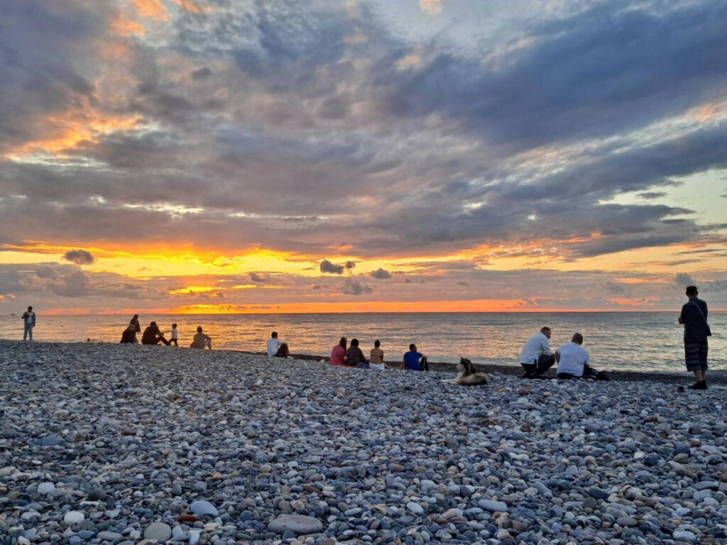 People enjoying the sunset views from the rocky shoreline