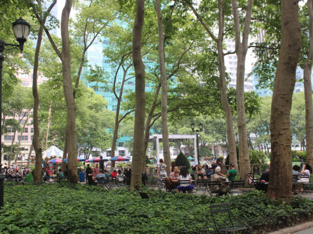 people relaxing under the shade surrounded by greenery at Bryant Park