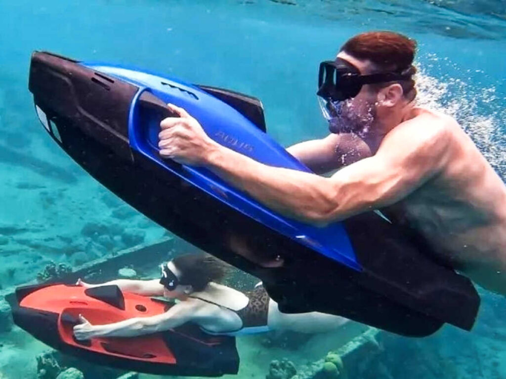 People riding a sea scooter under the water