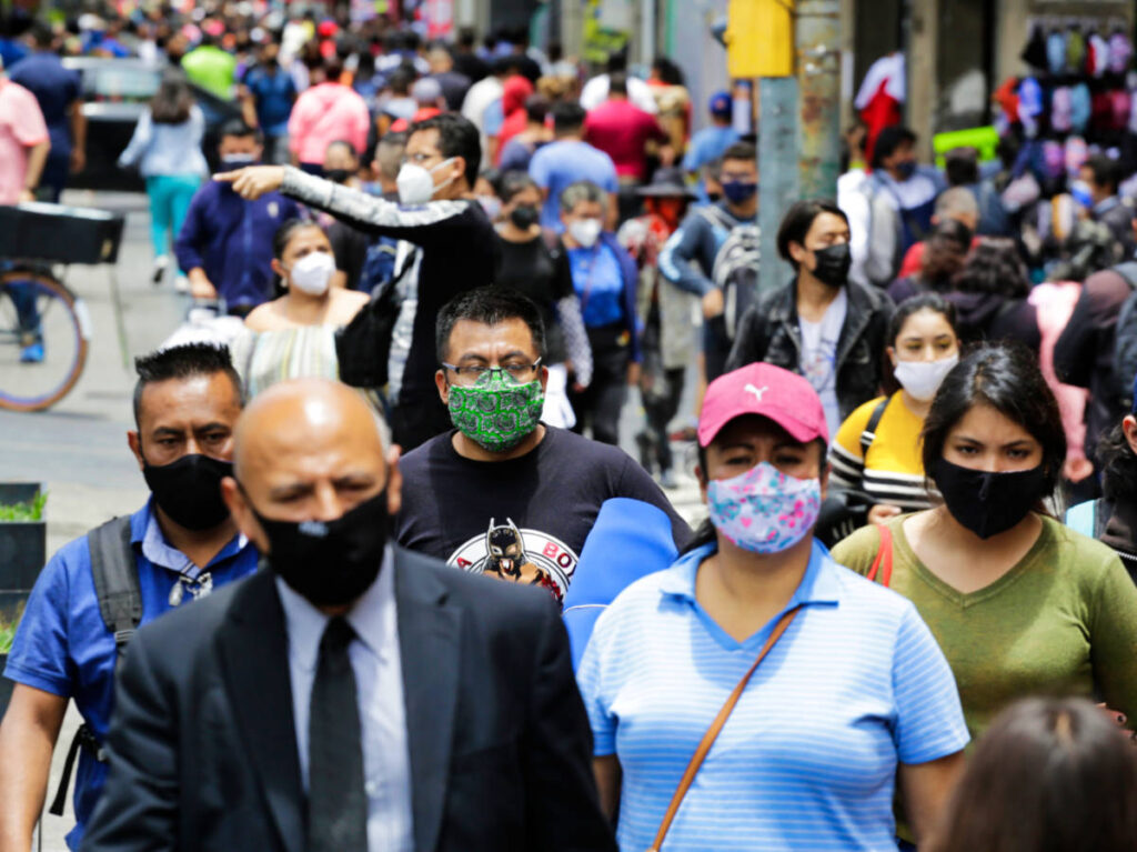 View of the crowd wearing face masks while walking in the street on a sunny day