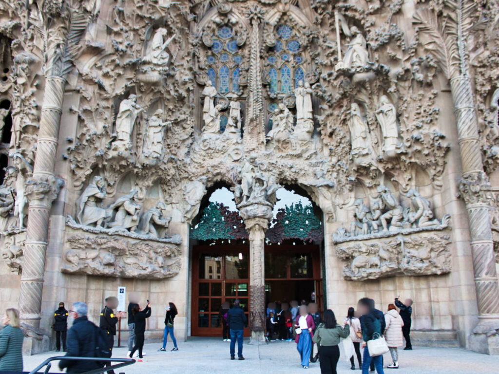 View of the people walking and taking a photo of the intricate sculptures at the front door of La Sagrada Familia
