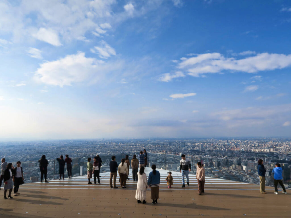 The people enjoying the overlooking view from the Shibuya Sky in Tokyo on a sunny day