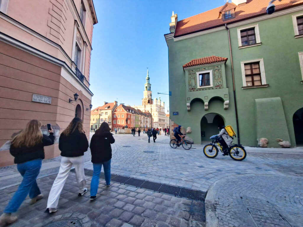 A group of people strolling and cycling on a cobblestone street at Stare Miasto