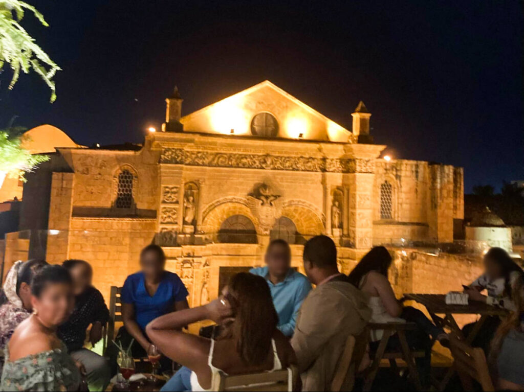 People drinking at the rooftop of Sugar Cane with the view of the Cathedral at night