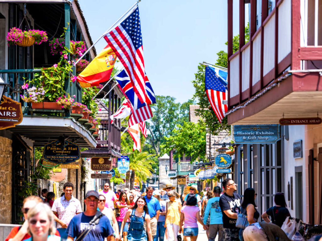 People walking together on a bustling street with flags around