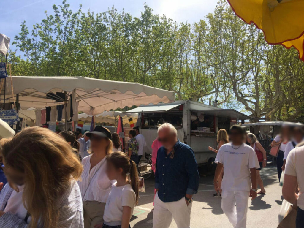 A crowd of people walking down a street in central Saint-Tropez