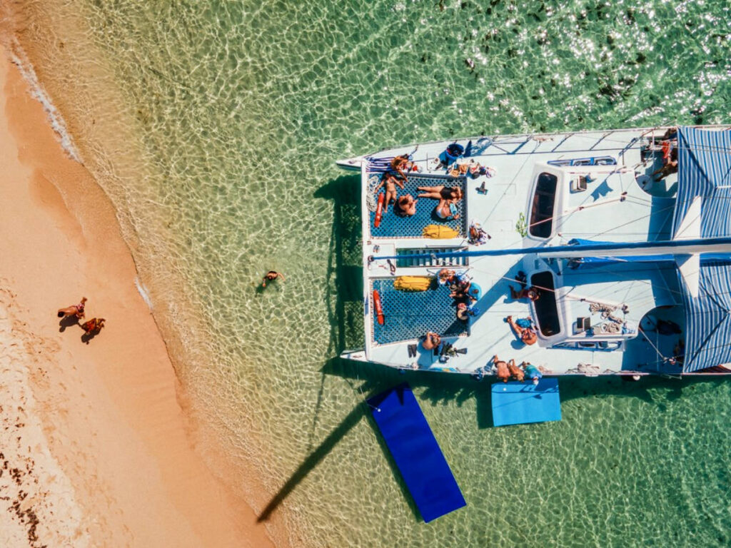 Aerial view of the tourists enjoying on the docked catamaran near the coast