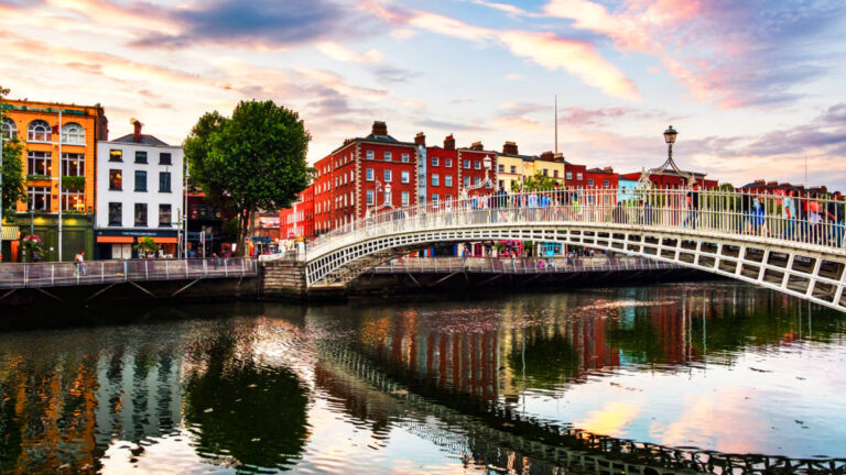 View of the people crossing the river on Ha'penny Bridge with the colorful buildings in the background