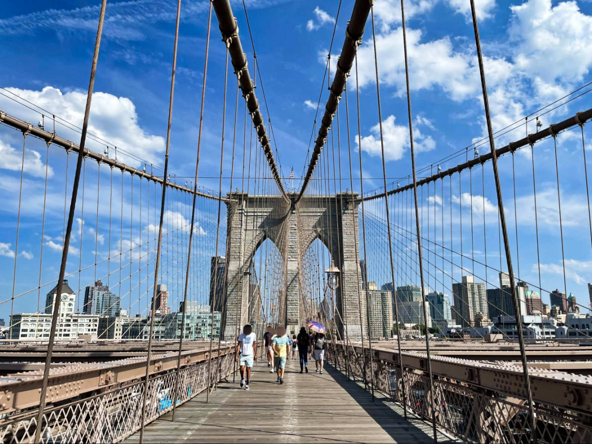 People walking on the Brooklyn Bridge on a sunny day