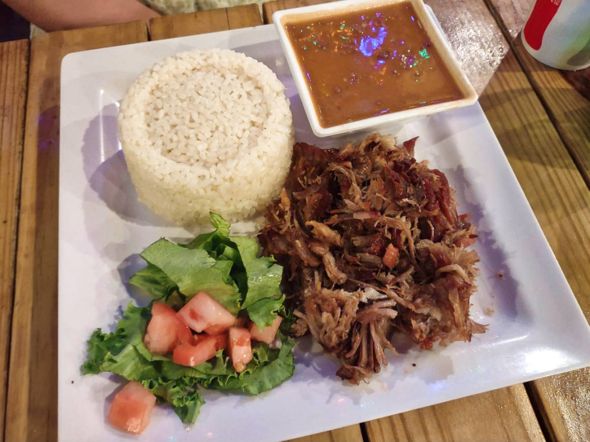 A plate with shredded pernil, rice and beans