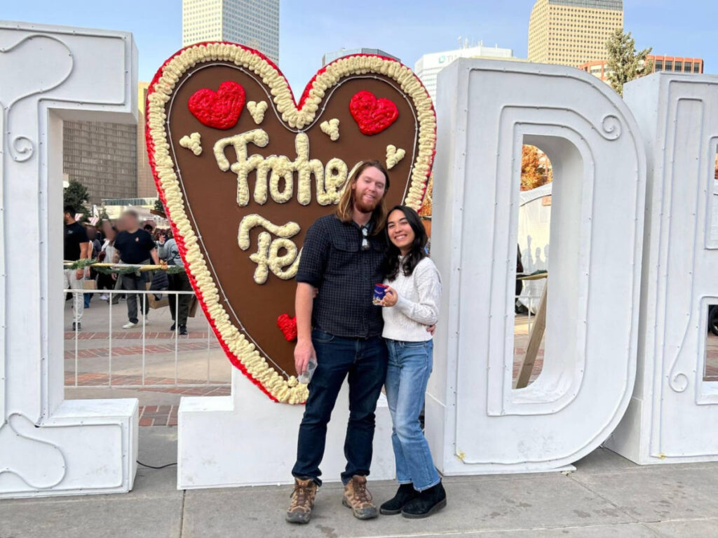 Travel Lemming Editor, Abigail Bliss and her husband posing for a photo in front of the heart shaped signage at Christkindlmarket