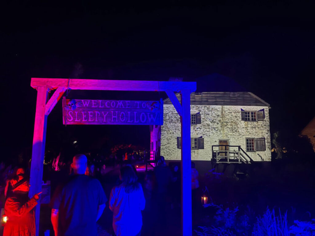 People entering the Sleepy Hollow with a view of Philipsburg Manor at night