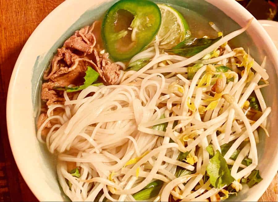 A bowl of pho tai with thinly sliced steak and vegetables in Pho Café