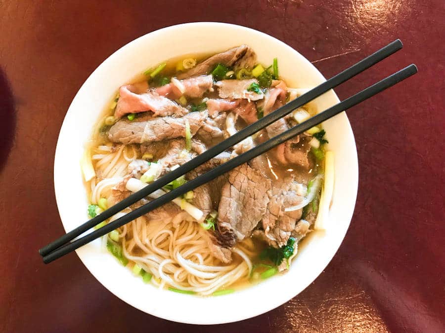 A bowl of pho soup with chopsticks placed on top