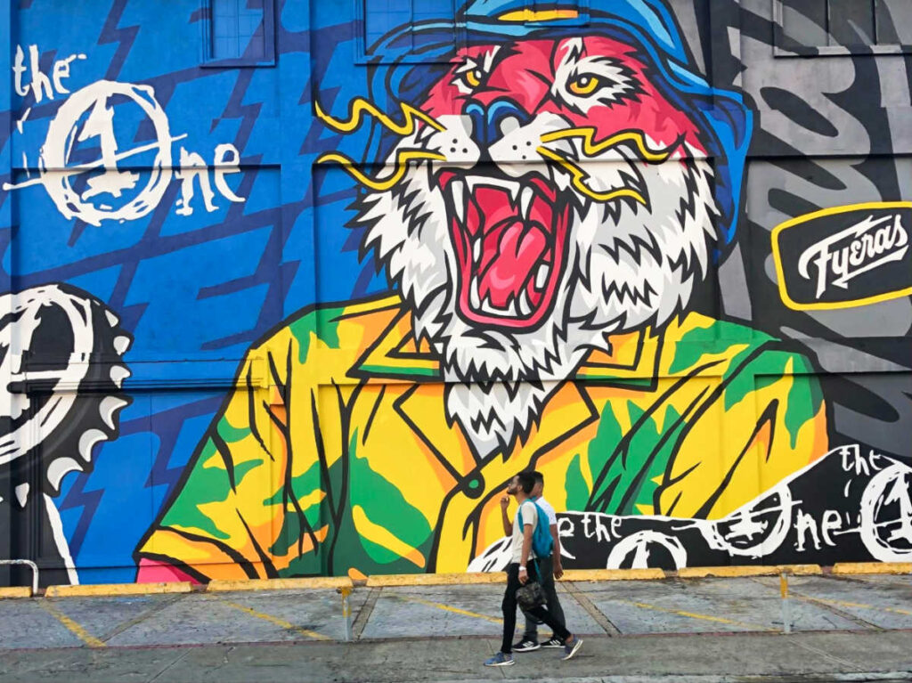 People walking along the huge street wall of art mural