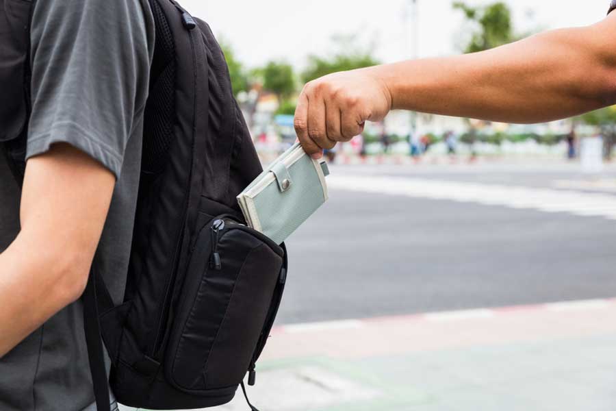 A man stealing a wallet from a backpack